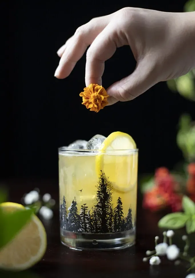 יד שמוסיפה פרח כתום לקוקטייל' title=