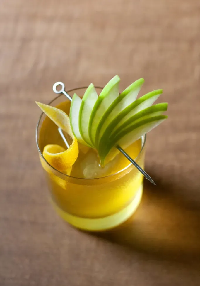 un primer plano de un abanico de rodajas de manzana verde en una selección de cócteles.' title=