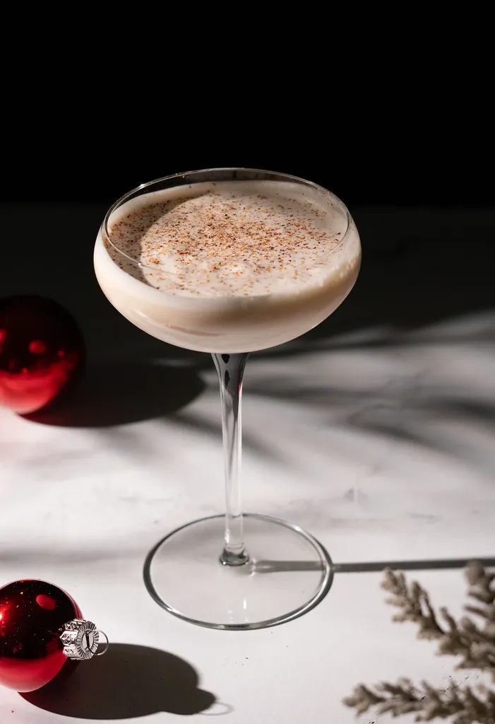 위에 갈색 육두구 조각을 얹은 칵테일 글라스에 담긴 옅은 크림 음료.' title=
