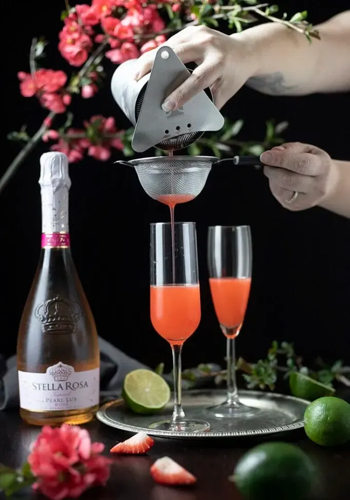 filtrer le cocktail dans des flûtes à champagne' title=