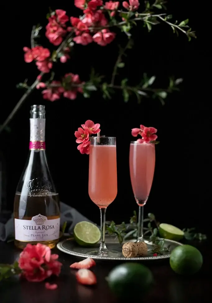deux cocktails roses dans des flûtes à champagne à côté d'une bouteille de Stella Rosa' title=