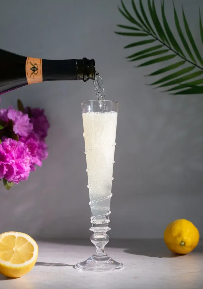 플루트 잔에 스파클링 와인을 붓는 모습.' loading='lazy' title=