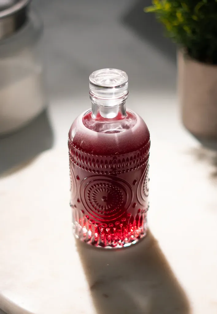 赤い液体のヴィンテージのガラス瓶の接写。' loading='lazy' title=