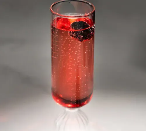 淡い赤色の泡状の飲み物で満たされたシャンパンフルート。' title=