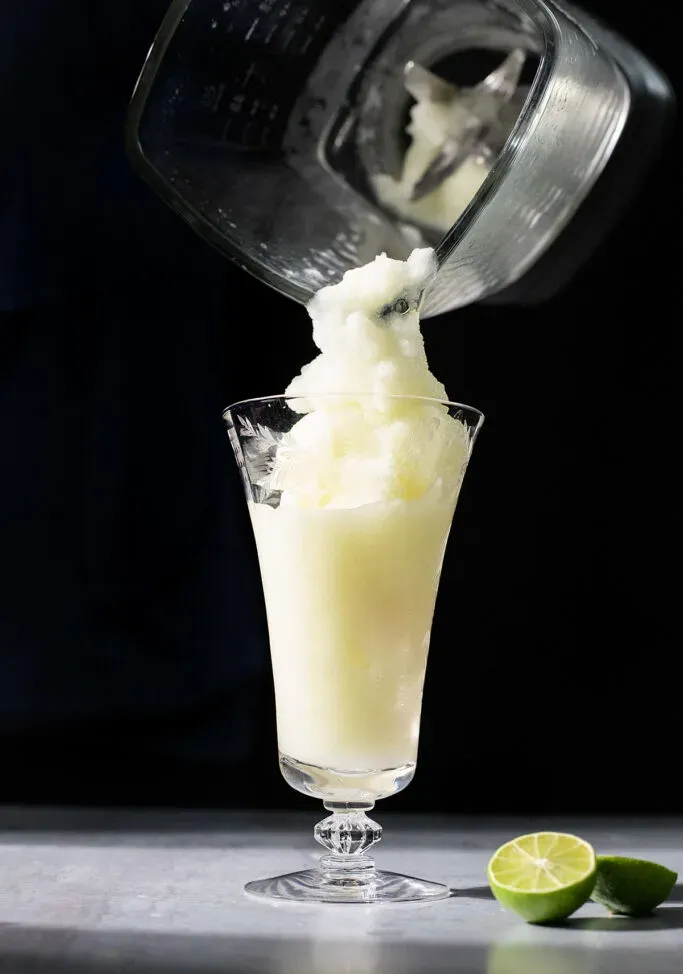 versando una bevanda ghiacciata in un bicchiere alto.' loading='lazy' title=