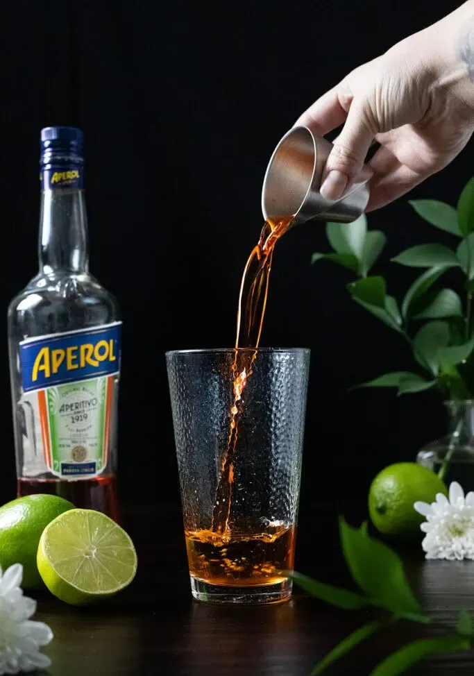 nalití unce Aperolu do míchací sklenice.' title=