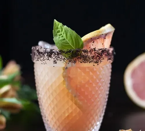 coquetel rosa em copo duplo com toranja e folha de manjericão' title=