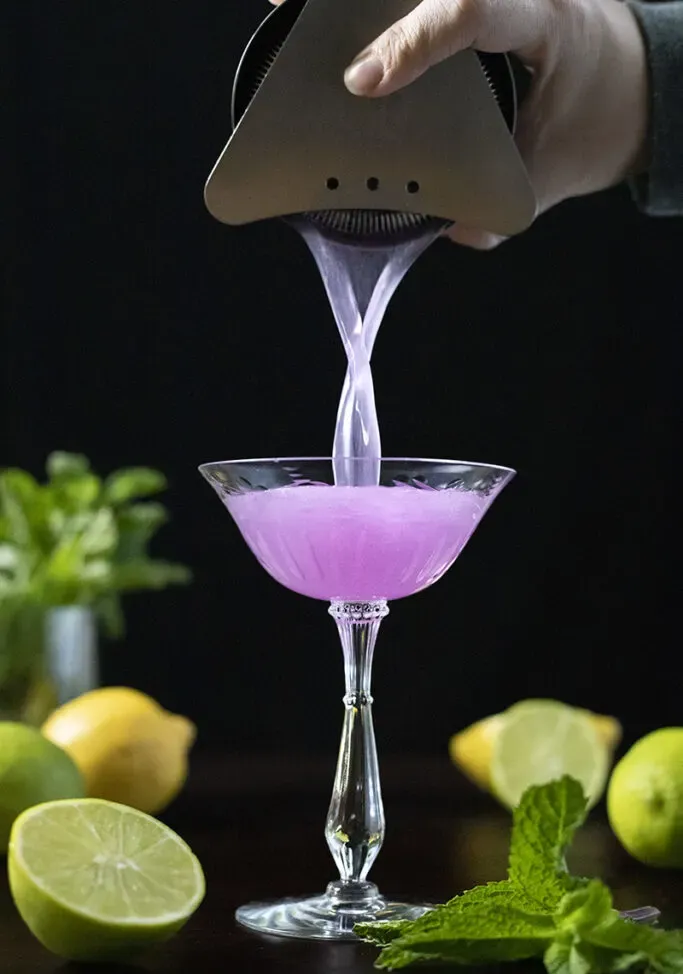 verser un cocktail violet vif dans un verre coupé' loading='lazy' title=