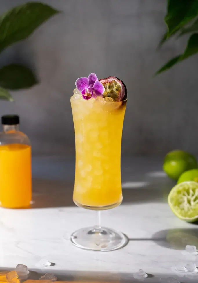 Ein großes gelbes tropisches Getränk in einem Hurricane-Glas.' title=