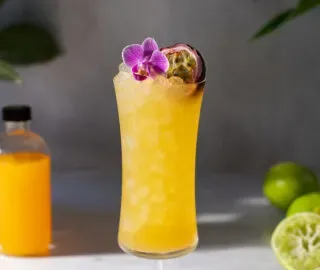 Ein großes gelbes tropisches Getränk in einem Hurricane-Glas.' title=