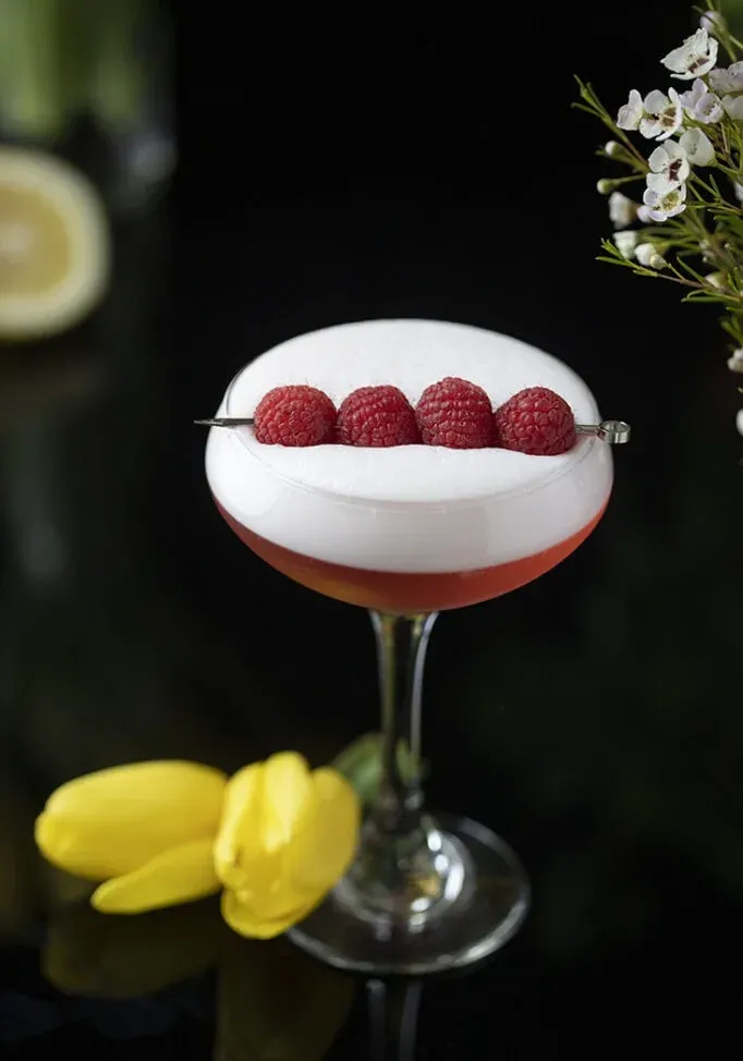 roter Cocktail mit dicker weißer Schaumkrone und Himbeeren' loading='lazy' title=