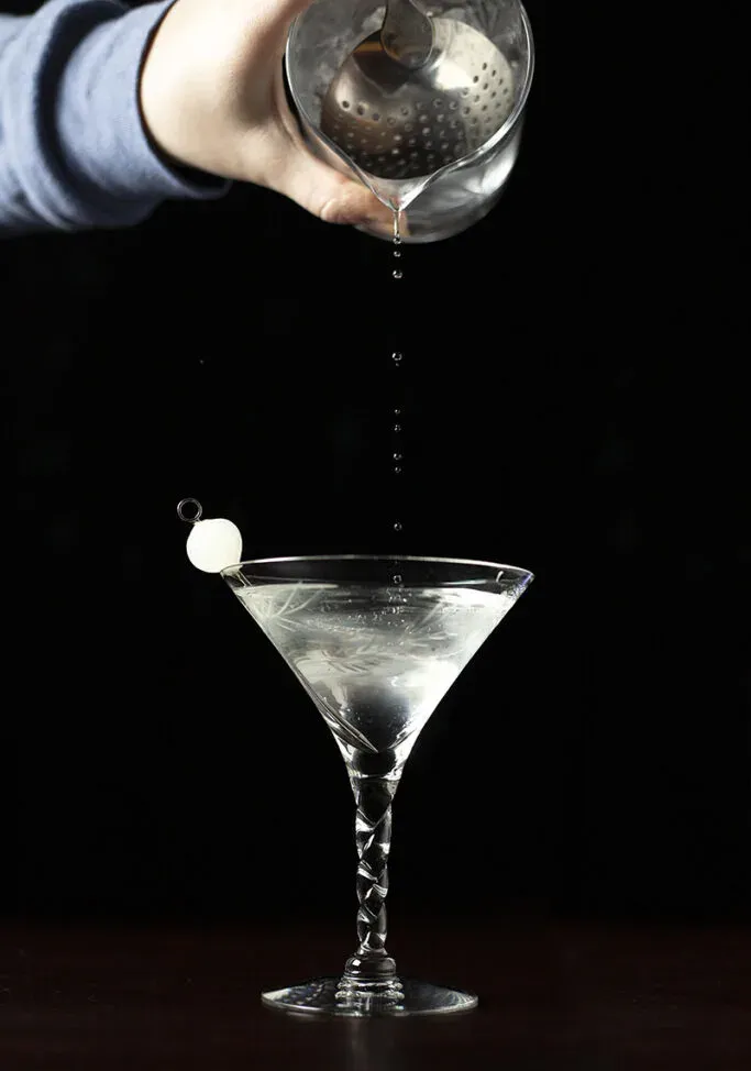 versare alcune gocce da un bicchiere da cocktail in una coppetta da martini' loading='lazy' title=