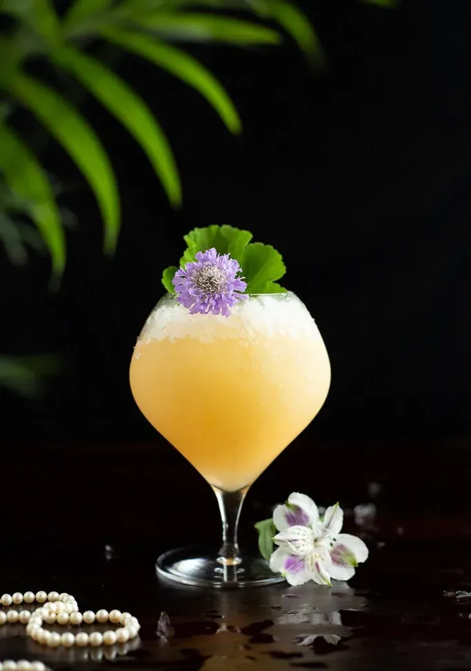 um coquetel Pearl Diver com uma flor comestível' title=