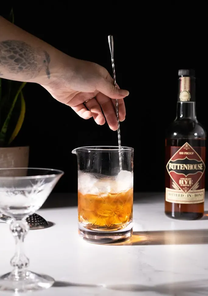 míchání whisky koktejlu s ledem a dlouhou barovou lžící.' title=