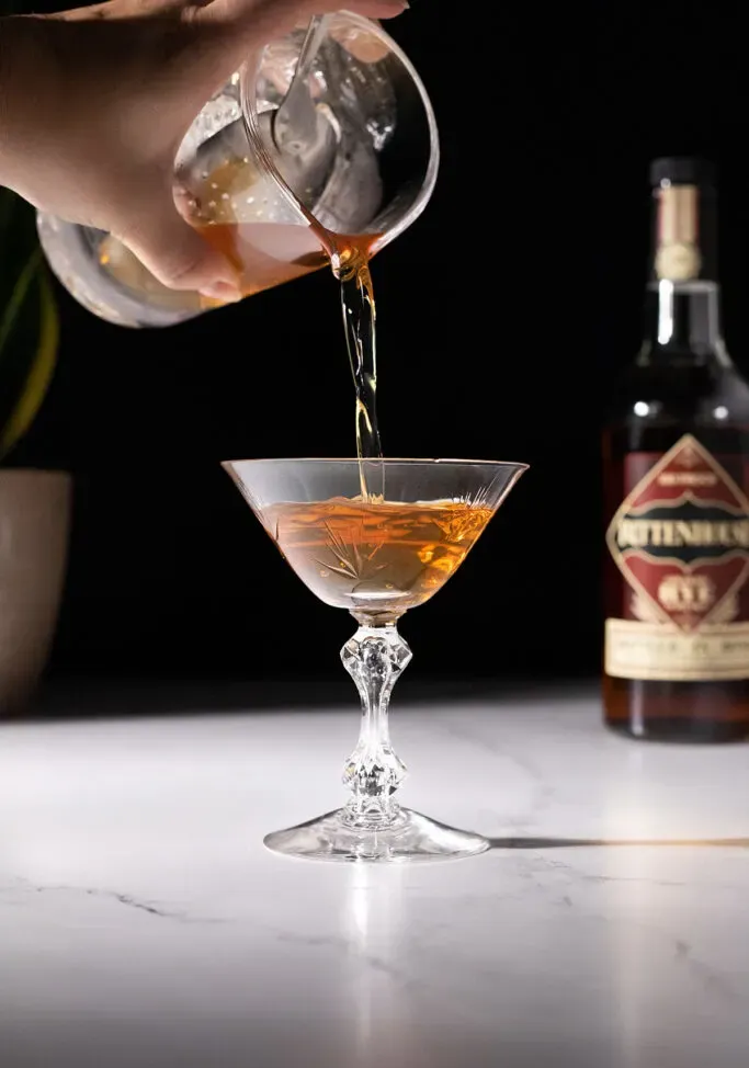 nalévání hnědého koktejlu do koktejlové sklenice.' title=