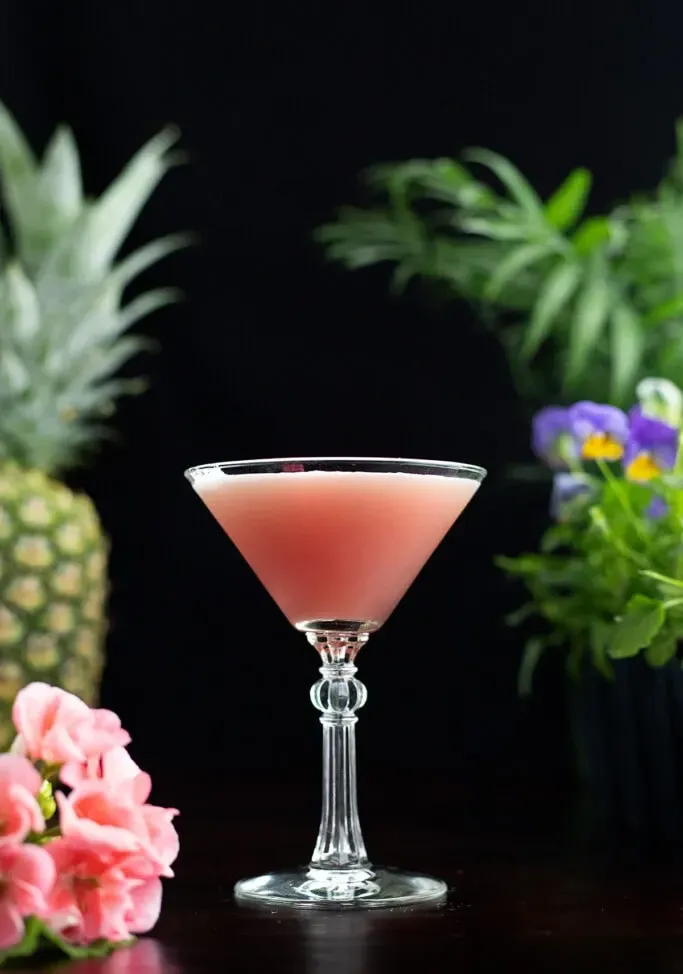 Ein rosafarbener Mary-Pickford-Cocktail mit Blumen' loading='lazy' title=