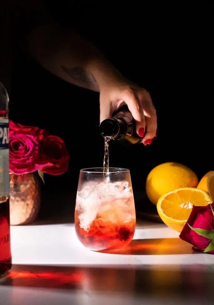 Gießen Sie Sekt in einen roten Cocktail in einem Weinglas ohne Stiel.' loading='lazy' title=