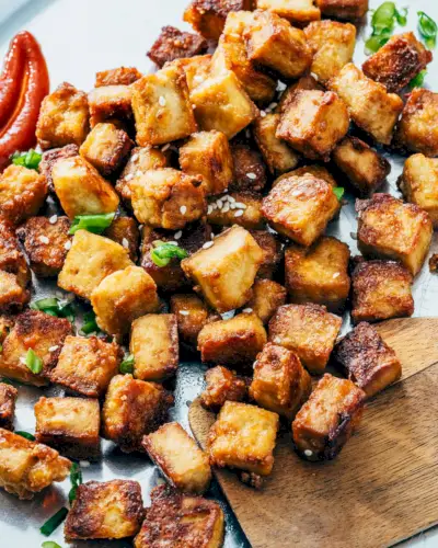 Receita de tofu assado em uma assadeira com espátula.