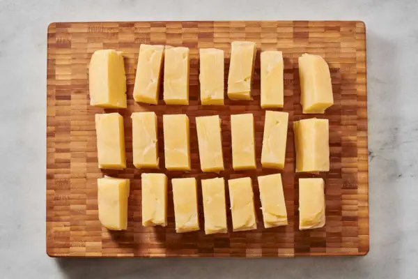 Uma tábua de corte com 21 pedaços iguais de bolos de batata cozidos com gordura de pato