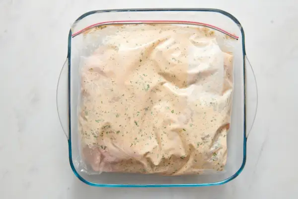 Ein großer Reißverschlussbeutel mit zwei Hähnchenhälften, mariniert in Joghurtsauce
