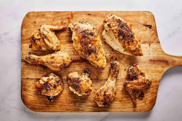 Una tabla de cortar con trozos de hierba tallada y pollo asado al limón.