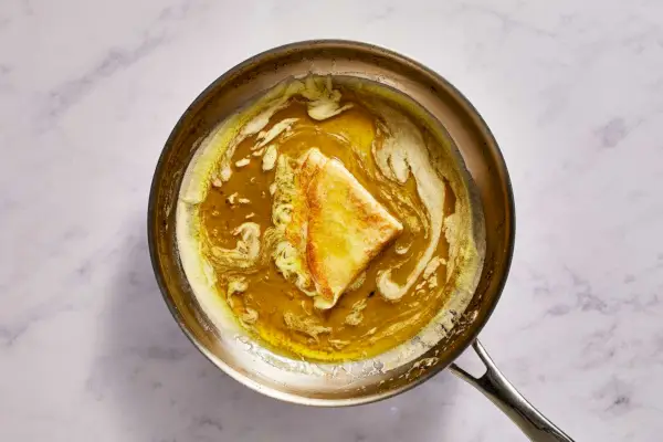 Eine große Pfanne mit einem gefalteten Crêpe in Butter-Orangen-Sauce