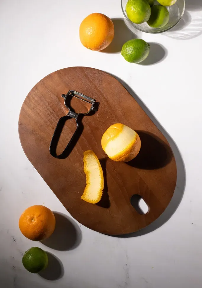 un pelador de verduras junto a una naranja y una cáscara de naranja' title=