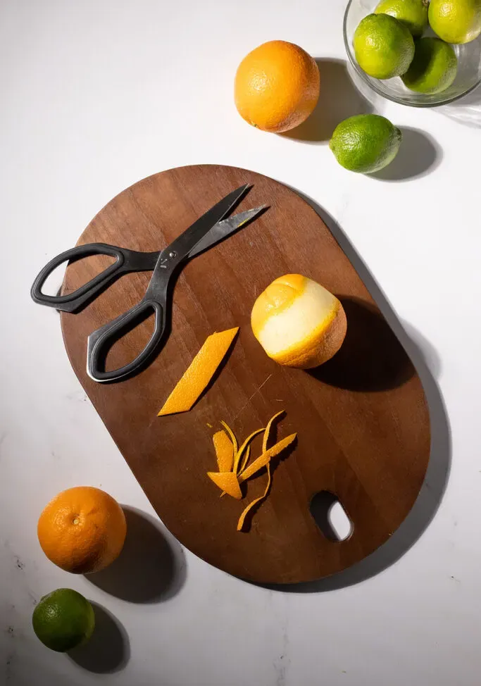 una cáscara de naranja recortada cortada en un rectángulo junto a unas tijeras.' title=