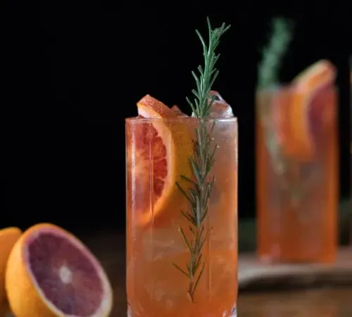 שתי כוסות הייבול במילוי משקה תפוז ופרוסות תפוז דם.' loading='lazy' title=