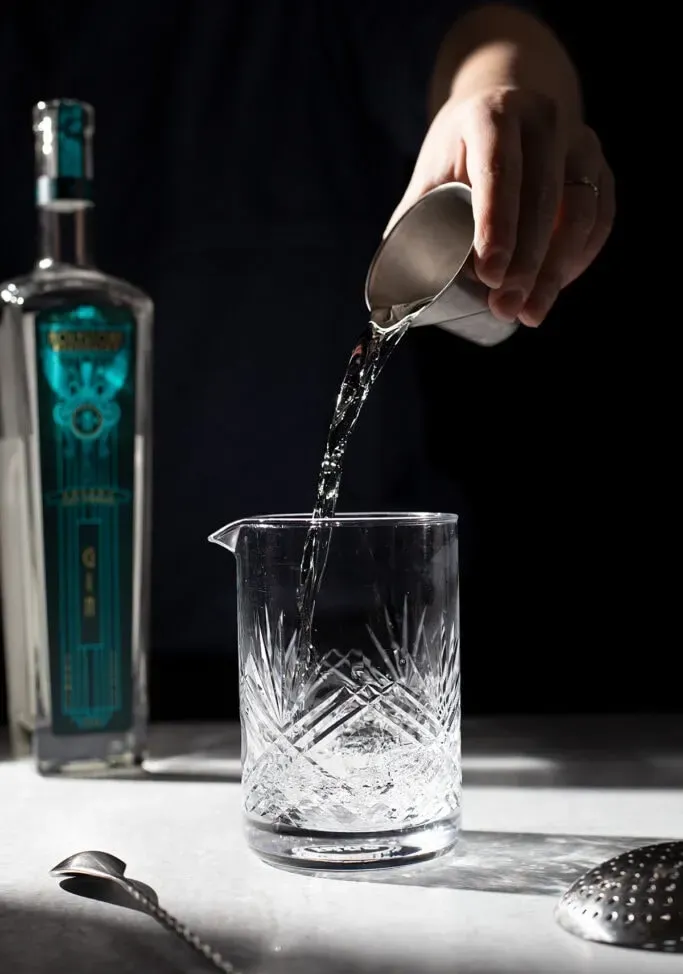 verser le gin d'un jigger dans un verre à mélange.' loading='lazy' title=