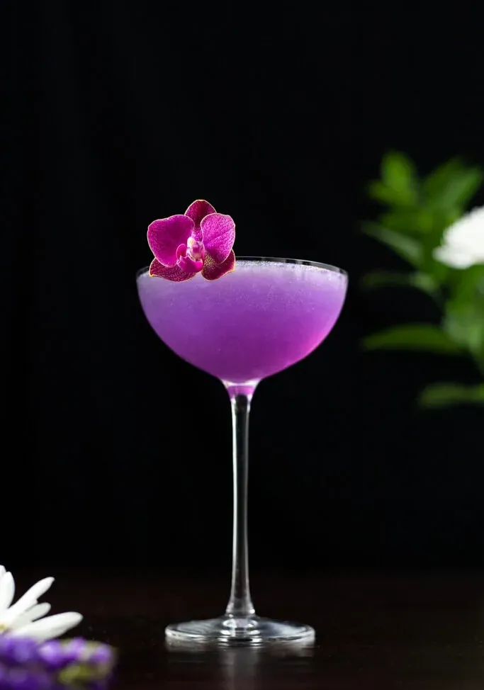 Lila-Veilchen-Pfirsich-Cocktail in einem Coupé-Glas.' title=