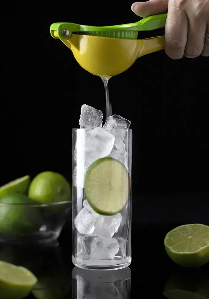 espremendo suco de limão com gelo em um copo alto.' title=