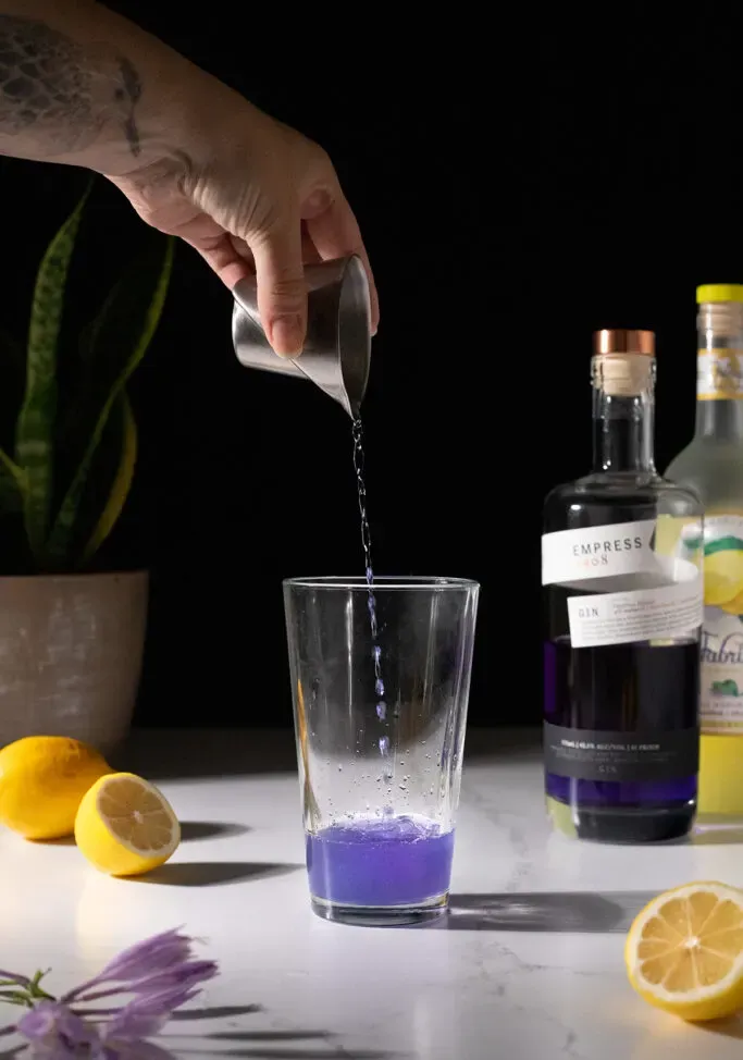 מוזגים ג'ין אמפרס סגול לתוך שייקר קוקטיילים.' title=