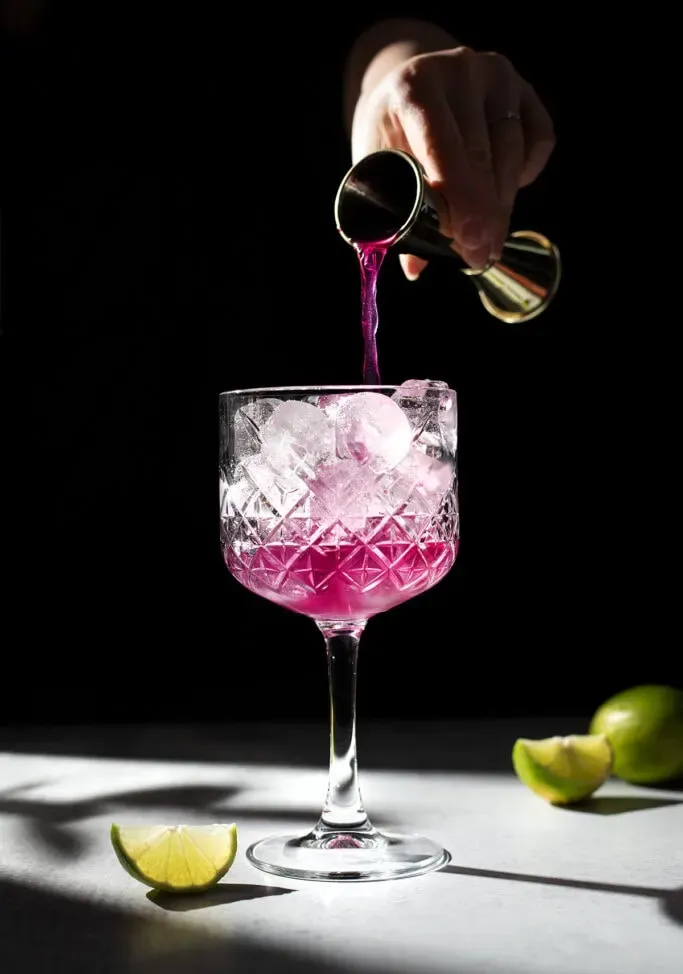 지거의 분홍색 액체를 얼음 위에 유리잔에 붓는다' loading='lazy' title=