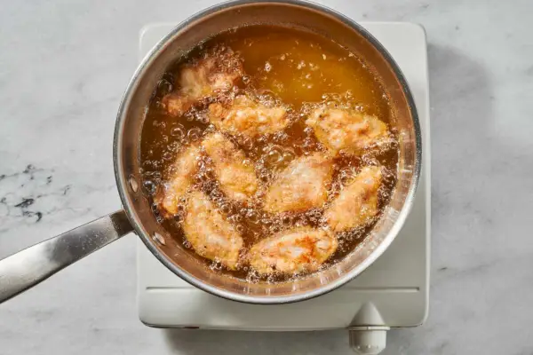 Alitas de pollo fritas en una olla grande con aceite