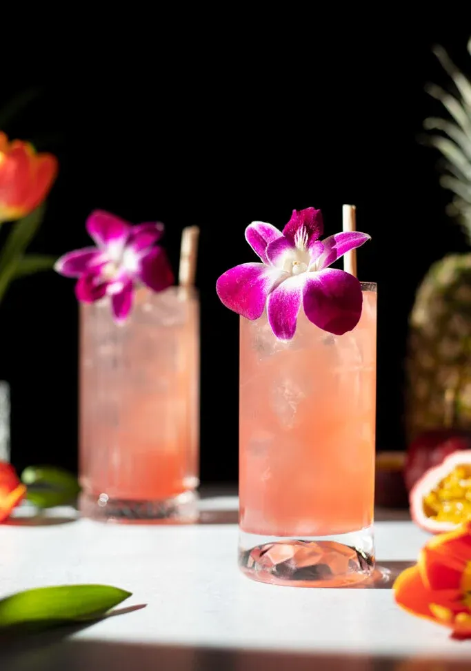 großes rosafarbenes Getränk mit Orchideengarnitur und einem Strohhalm.' title=