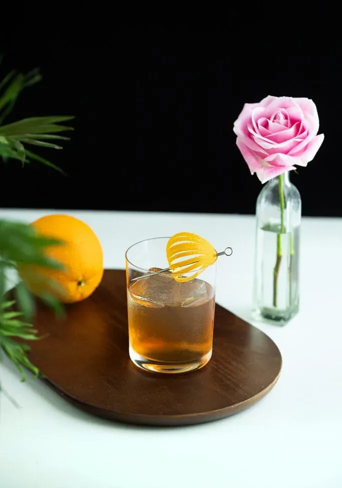 오렌지와 함께 커팅 보드에 있는 바위 위의 음료.' loading='lazy' title=