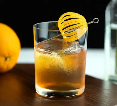멋진 오렌지 껍질을 곁들인 록 글라스에 담긴 위스키 칵테일.' title=