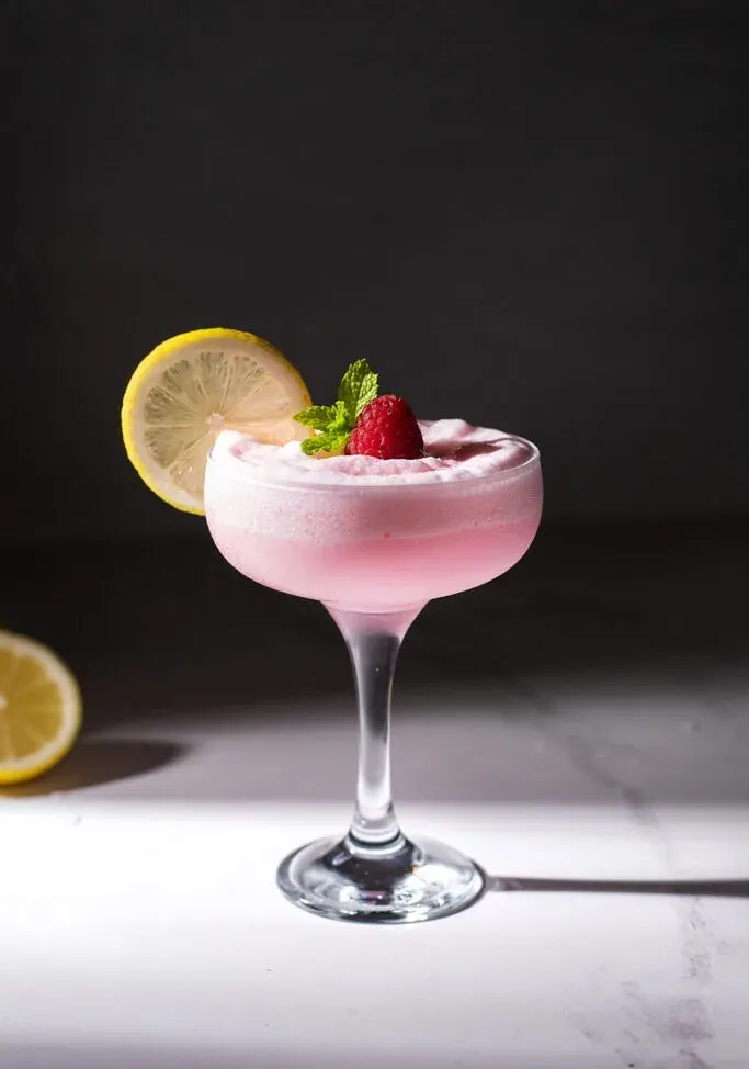 duża szklanka coupe wypełniona mrożoną różową lemoniadą.' title=