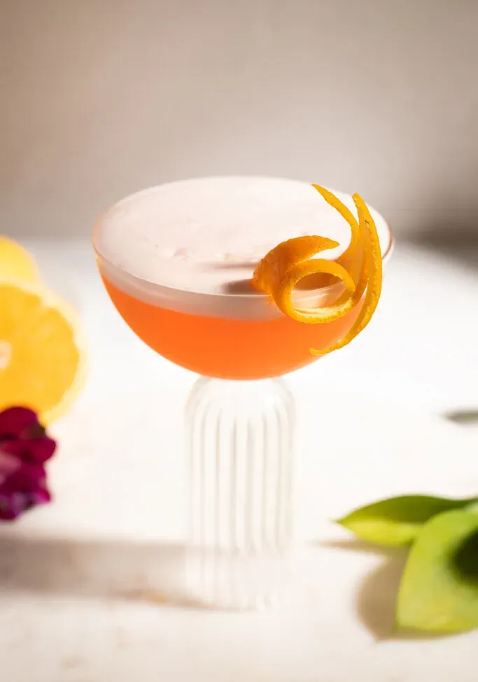 pohľad na bielu penu a efektný oranžový zákrut na vrchu Aperolu Sour.' title=