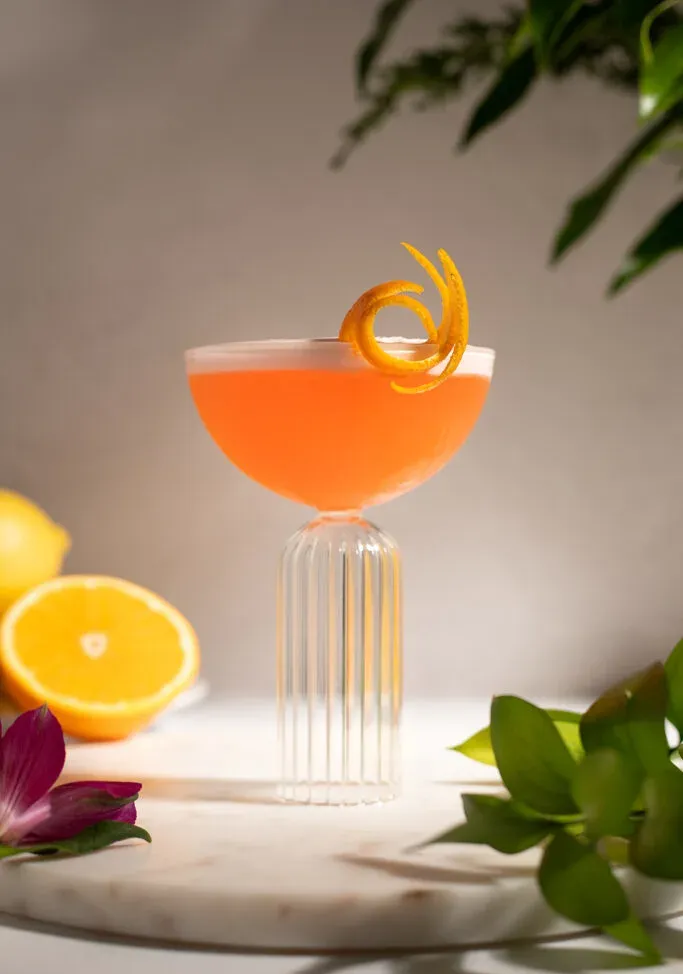 jasne oranžová tekutina v elegantnom pohári kupé s efektným oranžovým nádychom.' title=