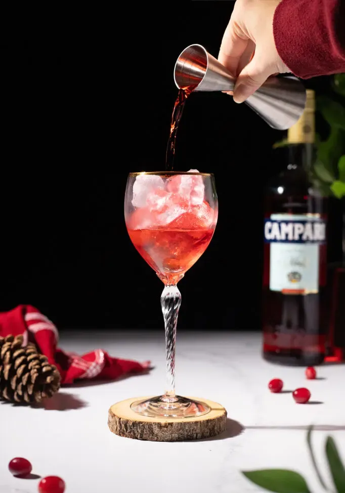 versare il liquore rosso in un bicchiere da vino pieno di ghiaccio.' loading='lazy' title=