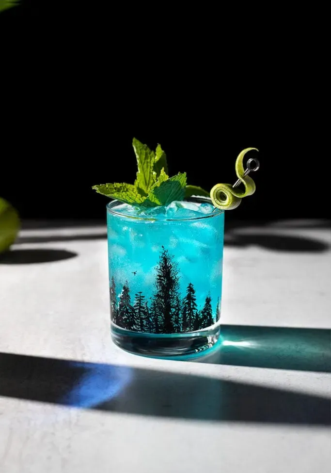 niebieski napój z gałązką mięty i fantazyjnym akcentem limonki.' title=