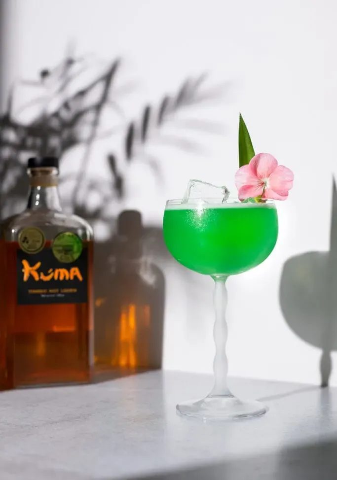 uma margarita verde ao lado de uma garrafa de licor de cúrcuma Kuma.' loading='lazy' title=