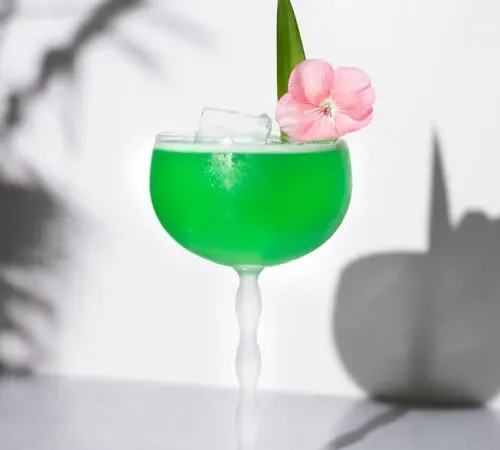 una bebida verde neón en un vaso alto.' title=