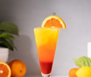 plzeňská sklenice s vrstveným červeným a oranžovým nápojem.' title=