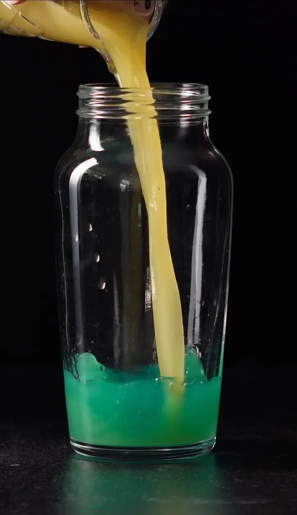 יוצקים מיץ אננס צהוב לנוזל כחול בשייקר קוקטיילים.' loading='lazy' title=