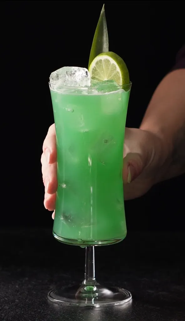 יד מרימה קוקטייל טרופי ירוק עז בכוס הוריקן.' title=
