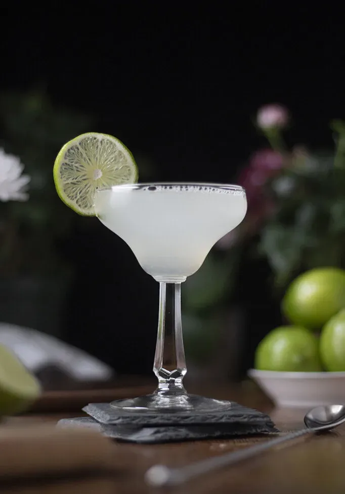 un cóctel en una copa de margarita vintage con una rodaja de lima.' title=