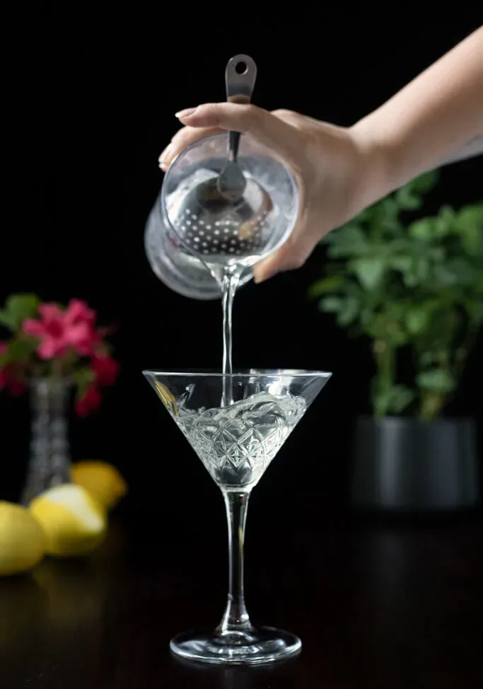 vertiendo un martini en una copa de cóctel' title=